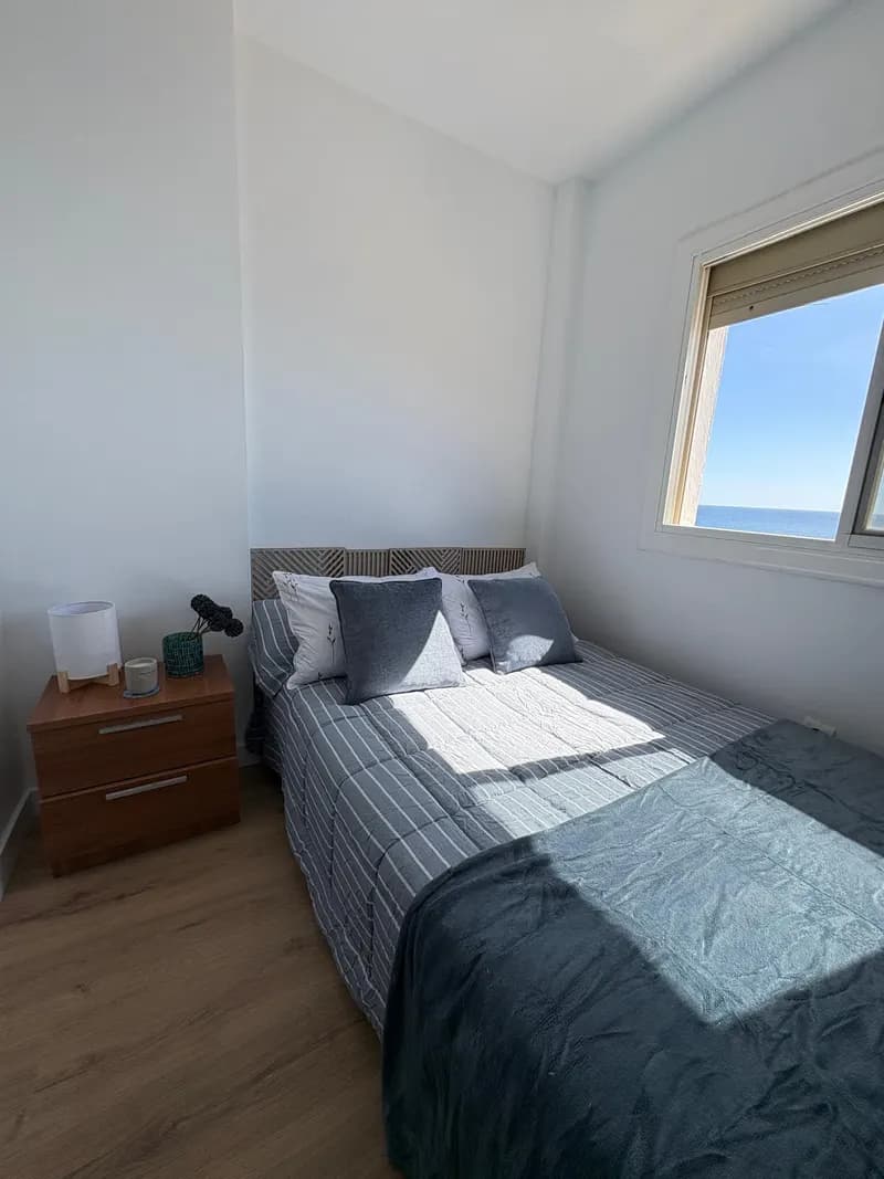 Dormitorio con textiles azules y ventana al mar
